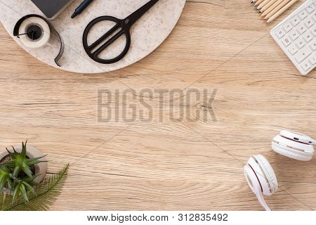 Office Table Desk Top View With Stationery, Notebook,headphone,plant,noteapd And Caculator On Wooden