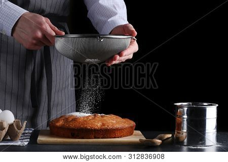 Chef Pouring Powdered Sugar On Tasty Pie On Dark Background. Ched Processing Pie Or Cake