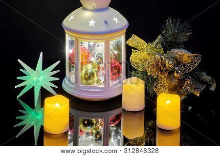 Christmas Burning Lanterns And Candles With Spruce Branch On A Black Background. Reflected On The Ta