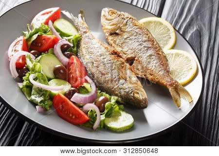 Natural Healthy Food Fried Salema Porgy Fish With Lemon And Fresh Vegetable Salad Close-up On A Plat