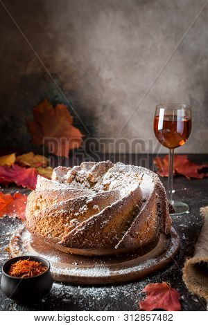 Bundt Cake With Saffron And Rum Covered With White Glaze On Rustic Background With Autumn Decoration