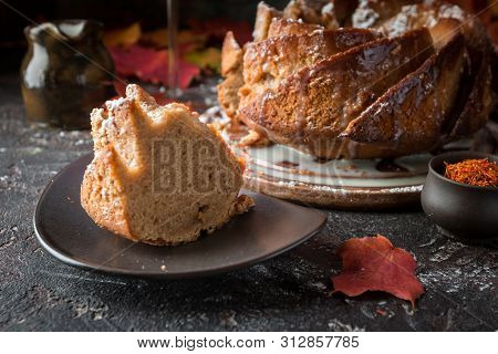 Bundt Cake With Saffron And Rum Covered With White Glaze On Rustic Background With Autumn Decoration