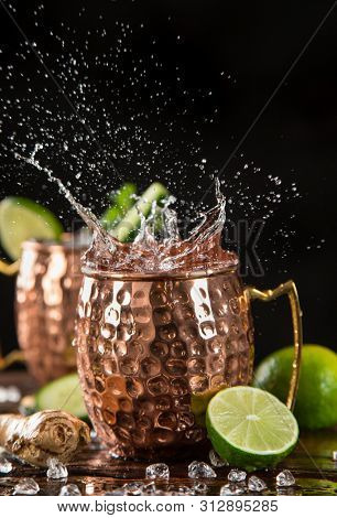 Famous splashing Moscow mule alcoholic cocktail in copper mugs, freeze motion effect.