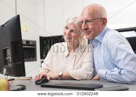 Happy Elder Couple Enjoy Together At Computer. Seniors Use A Computer, They Look At The Pictures The