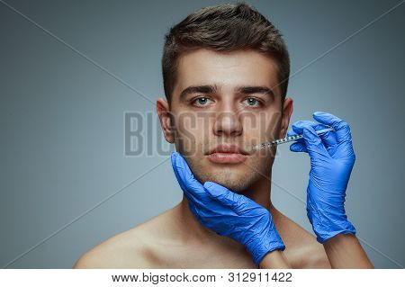 Close-up Portrait Of Young Man Isolated On Grey Studio Background. Filling Surgery Procedure. Concep