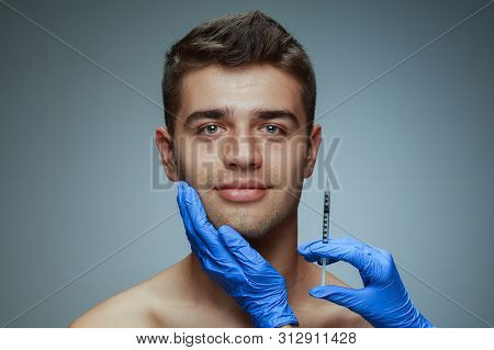 Close-up Portrait Of Young Man Isolated On Grey Studio Background. Filling Surgery Procedure. Concep