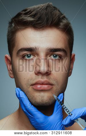 Close-up Portrait Of Young Man Isolated On Grey Studio Background. Filling Surgery Procedure. Concep