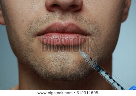 Close-up Portrait Of Young Man Isolated On Grey Studio Background. Filling Surgery Procedure. Concep