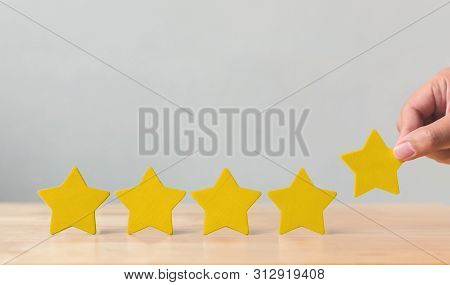 Hand Putting Wooden Five Star Shape On Table. The Best Excellent Business Services Rating Customer E