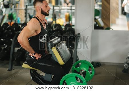 A Young Athlete Trains In The Gym. Trians Biceps Muscules