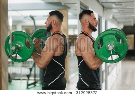 A Young Athlete Trains In The Gym. Trians Biceps Muscules