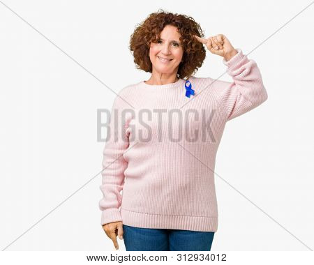 Middle ager senior woman wearing changeable blue color ribbon awareness over isolated background Smiling pointing to head with one finger, great idea or thought, good memory