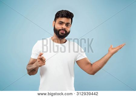 Half-length Close Up Portrait Of Young Hindoo Man In White Shirt On Blue Background. Human Emotions,