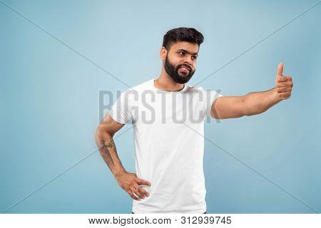 Half-length Close Up Portrait Of Young Hindoo Man In White Shirt On Blue Background. Human Emotions,