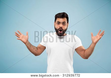 Half-length Close Up Portrait Of Young Hindoo Man In White Shirt On Blue Background. Human Emotions,