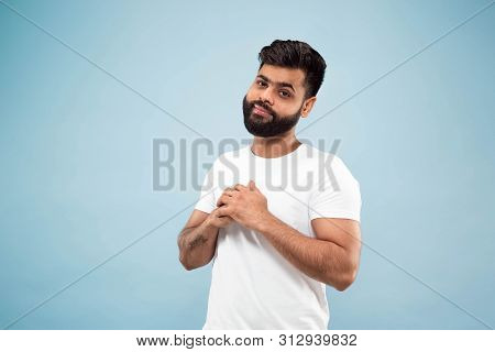 Half-length Close Up Portrait Of Young Hindoo Man In White Shirt On Blue Background. Human Emotions,