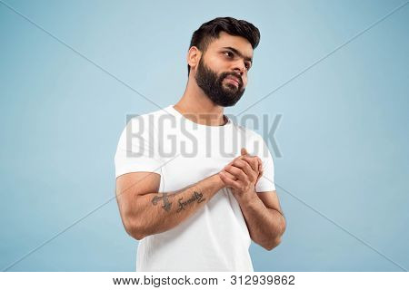 Half-length Close Up Portrait Of Young Hindoo Man In White Shirt On Blue Background. Human Emotions,
