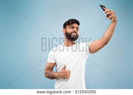 Half-length Close Up Portrait Of Young Hindoo Man In White Shirt On Blue Background. Human Emotions,
