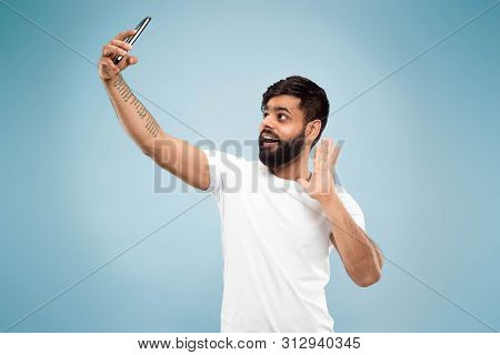 Half-length Close Up Portrait Of Young Hindoo Man In White Shirt On Blue Background. Human Emotions,