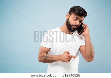 Half-length Close Up Portrait Of Young Hindoo Man In White Shirt On Blue Background. Human Emotions,