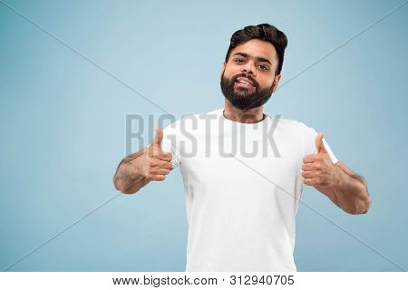 Half-length Close Up Portrait Of Young Hindoo Man In White Shirt On Blue Background. Human Emotions,