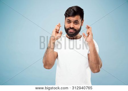 Half-length Close Up Portrait Of Young Hindoo Man In White Shirt On Blue Background. Human Emotions,