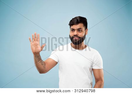 Half-length Close Up Portrait Of Young Hindoo Man In White Shirt On Blue Background. Human Emotions,