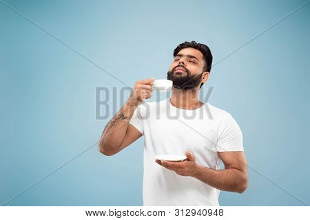 Half-length Close Up Portrait Of Young Hindoo Man In White Shirt On Blue Background. Human Emotions,