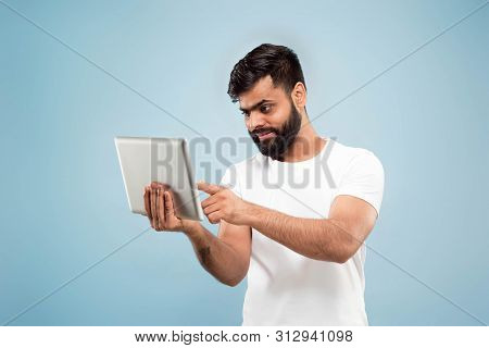 Half-length Close Up Portrait Of Young Hindoo Man In White Shirt On Blue Background. Human Emotions,