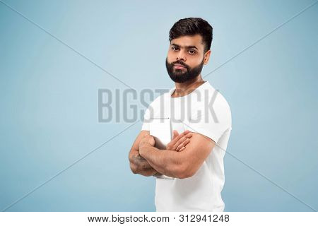 Half-length Close Up Portrait Of Young Hindoo Man In White Shirt On Blue Background. Human Emotions,