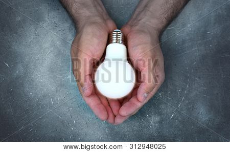 Concept Of Hope With Lighting Bulb In Strong Brutal Male Hands.