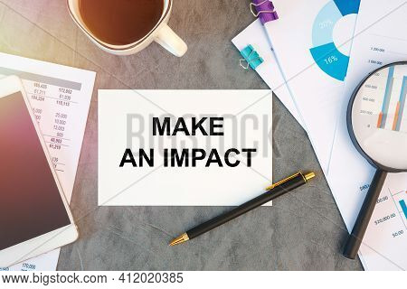 Make An Impact Is Written In A Document On The Office Desk With Office Accessories, Coffee, Diagram 