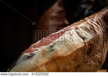 Jamon Serrano. Traditional Spanish Ham, Slicing Of Dry-cured Ham. Iberian Ham Cutter On Black Backgr