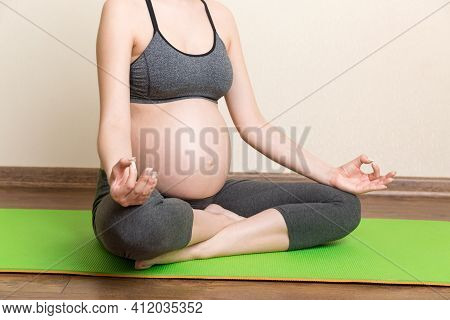 Beautiful Young Pregnant Woman Sitting On Mat In Yoga Pose At The Home. Pregnancy Yoga And Fitness C