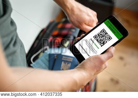 The woman holding the mobile phone a mockup for digital vaccination certificate in one hand and passport, mask and ticket in another one