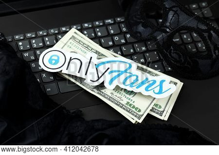 Kharkov, Ukraine - February 14, 2021: Onlyfans Paper Logo With Smartphone And Dollar Bills On Black 