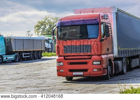 Semi-trailers Truks In A Row In The Parking Lot Against The Sky