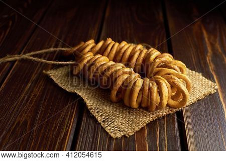 Wheat Bagels On A Rope On Burlap Cloth On Dark Wooden Table. Traditional Russian Food.