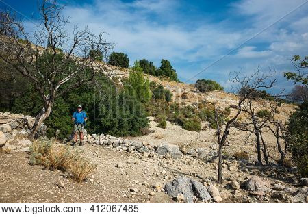 Hiking Lycian way. Man is standing on dry stony highland under dead tree on stretch between Kalkan and Kas of Lycian way trail, Trekking in Turkey, outdoor activity