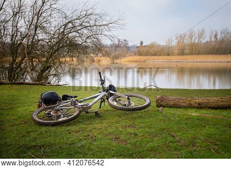 Mountain Bike Left On Grass Beside Lake On Bright February Day On Trail By The Great Story River Bet