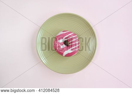 One Tasty Pink Glazed Doughnut On Beige Round Plate On Pink Background. Top View Of Appetizing Donut