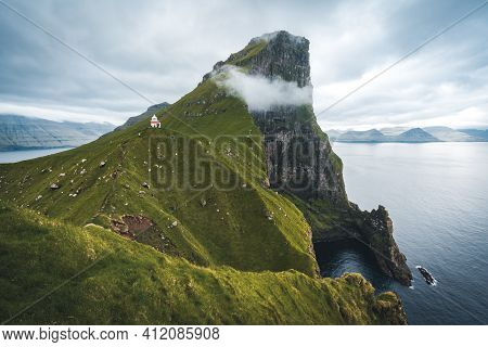 Kalsoy Island With Kallur Lighthouse On On Faroe Islands, Denmark, Europe. Clouds Over High Cliffs, 