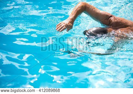 Senior man in his home swimming pool, enjoying the deserved retirement