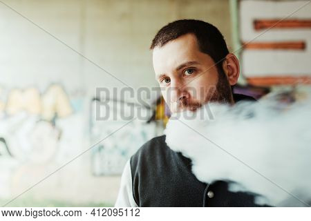 Caucasian White Man Looking At Camera While Vaping. Person Quitting Smoking. Clouds Of Vapor Caused 