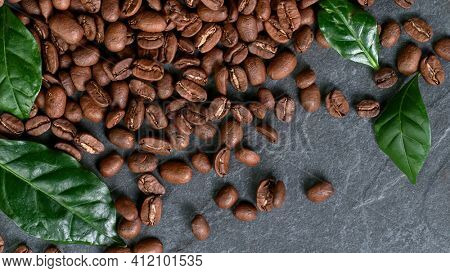 Falling Roasted Coffee Beans on Black Stone Background, close-up.
