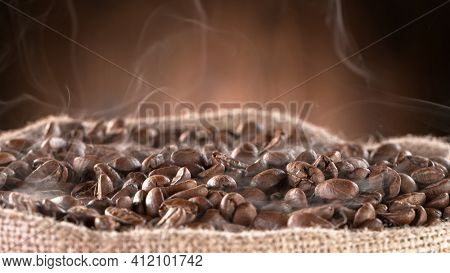 Falling Roasted Coffee Beans on Brown Background, close-up.
