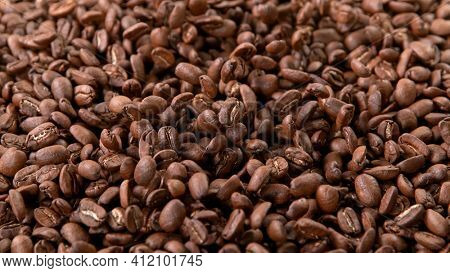 Falling Roasted Coffee Beans on Brown Background, close-up.