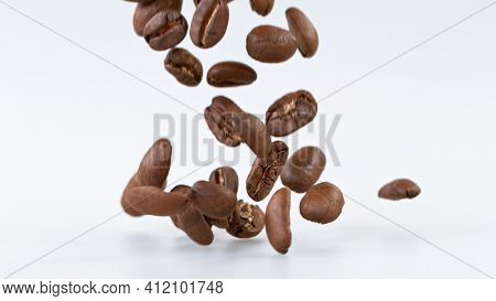 Falling Roasted Coffee Beans on White Background, close-up.