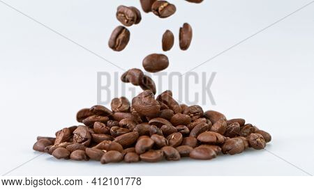 Falling Roasted Coffee Beans on White Background, close-up.