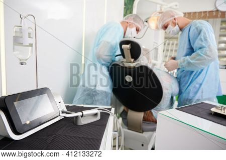Dentists Using Dental Implant Machine In Modern Dental Office.
